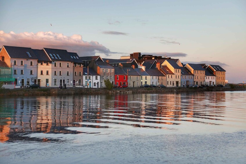 A row of houses by a calm body of water during sunset. 2