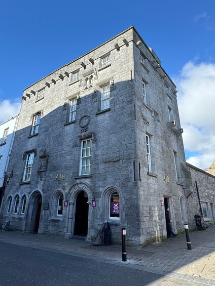 A historic stone building with arched windows and a clock. 4