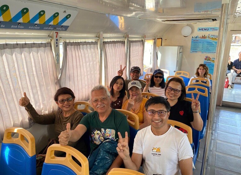 A group of people seated on a bus with a menu board and seat numbers visible. 2