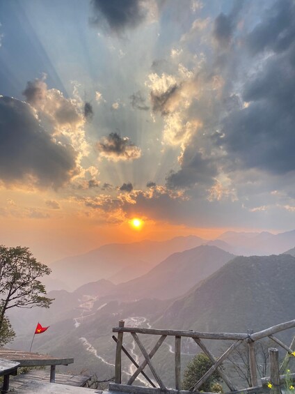 A sunset over mountains with a flag and a wooden fence. 5