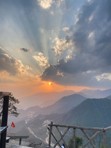A sunset over a mountainous landscape with a flag on a wooden structure. 2