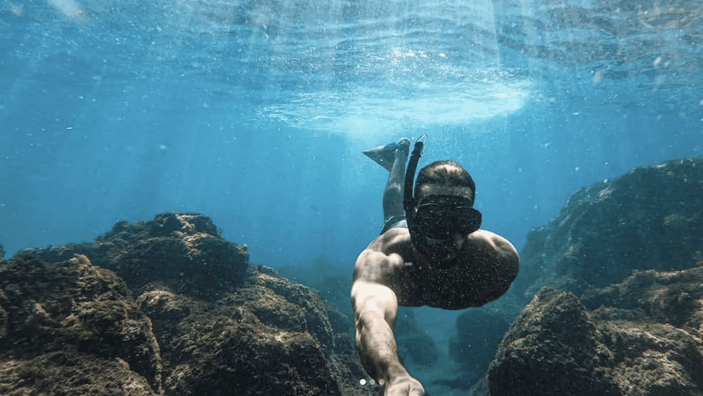 A diver underwater with rocky terrain. 5