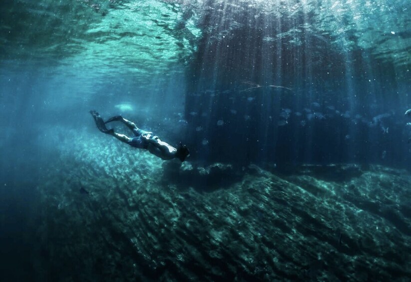A diver swimming underwater near a submerged structure. 4