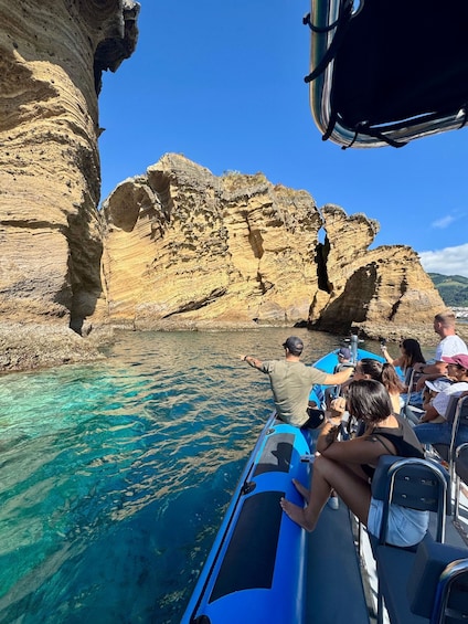 A boat tour with people enjoying the clear blue waters and rocky cliffs. 3