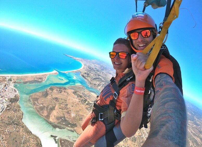 A person skydiving with a parachute, overlooking a coastal landscape with clear blue waters and sandy beaches. 1