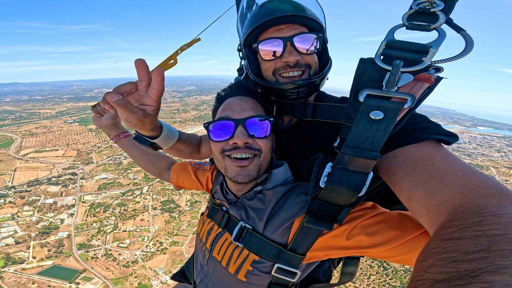 Two people skydiving with a landscape view below. 4