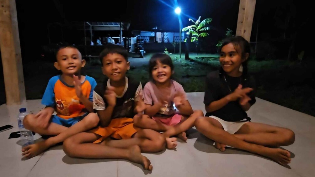 Four children sitting on a white surface outdoors at night. 1