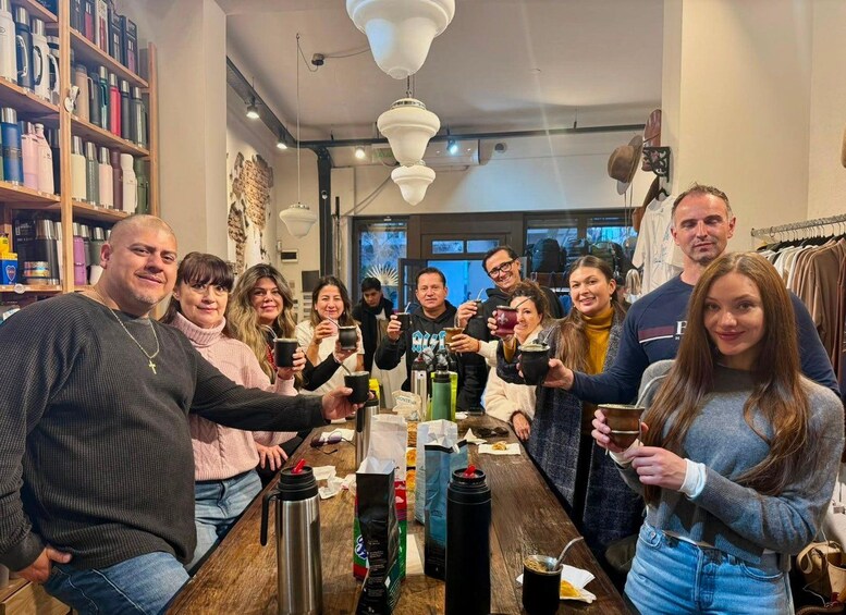 A group of people gathered around a table in a cafe, holding cups and engaging in conversation. 1