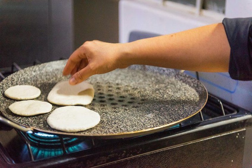 A hand placing a flatbread on a heated pan. 3