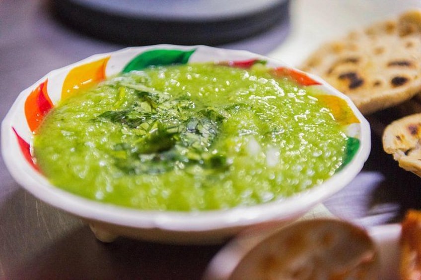 A bowl of green soup with herbs, accompanied by flatbread. 2