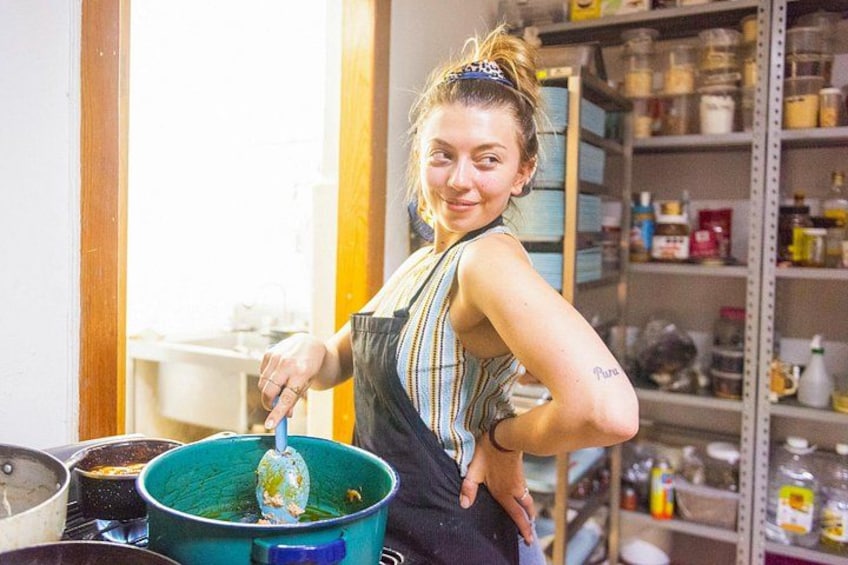 A person in a kitchen with a blue pot on the counter. 4