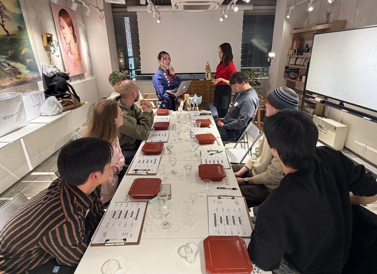 A group of people seated around a table in a modern meeting room with a presentation in progress. 3