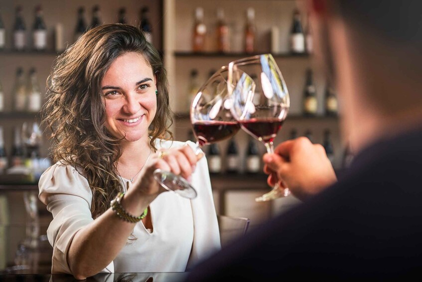 A person holding a wine glass at a bar with shelves of bottles in the background. 3