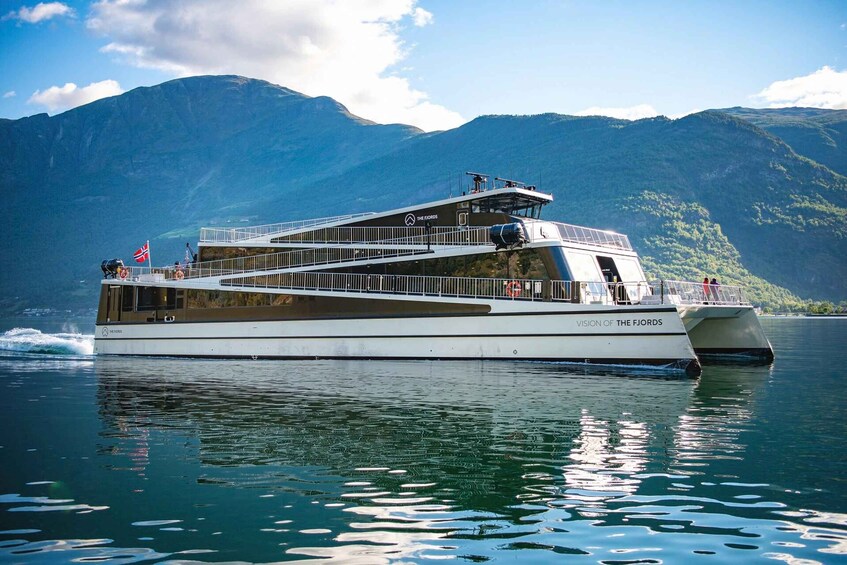 A large white boat named "Vision of the Fjords" on calm waters with mountains in the background. 1