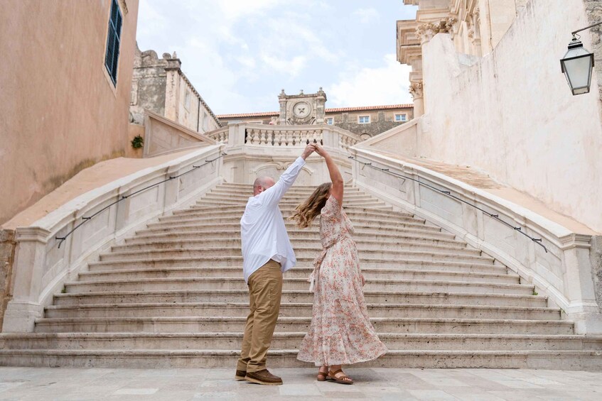 A couple dancing on a stone staircase with a clock tower in the background. 3