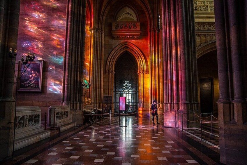 A cathedral interior with a checkered floor, large columns, and a person walking. 3