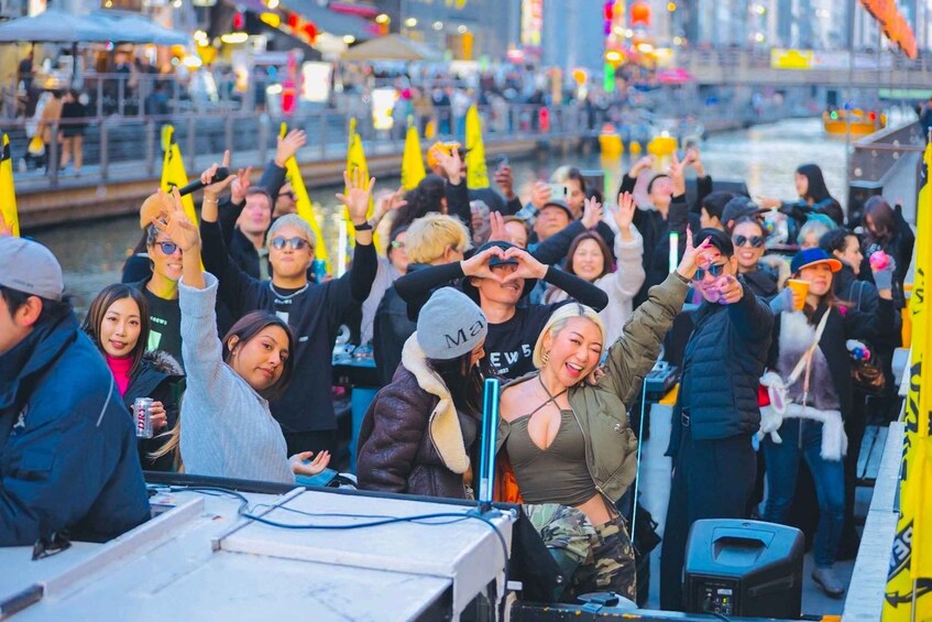 A crowd on a boat with people holding yellow flags, some making peace signs, and a river in the background. 5