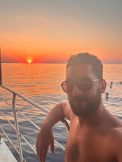 A man on a boat with a sunset in the background. 3