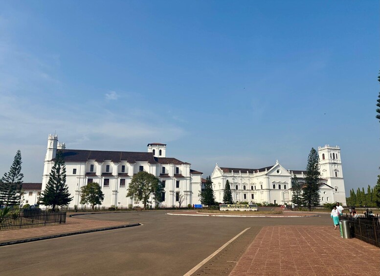 A large white colonial-style building with multiple towers and a central dome, surrounded by a paved plaza and trees. 5