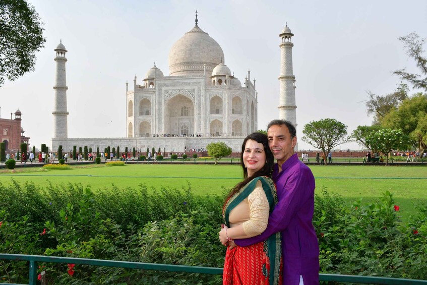 Een stel staat voor de Taj Mahal, met de iconische koepels en minaretten op de achtergrond. 1