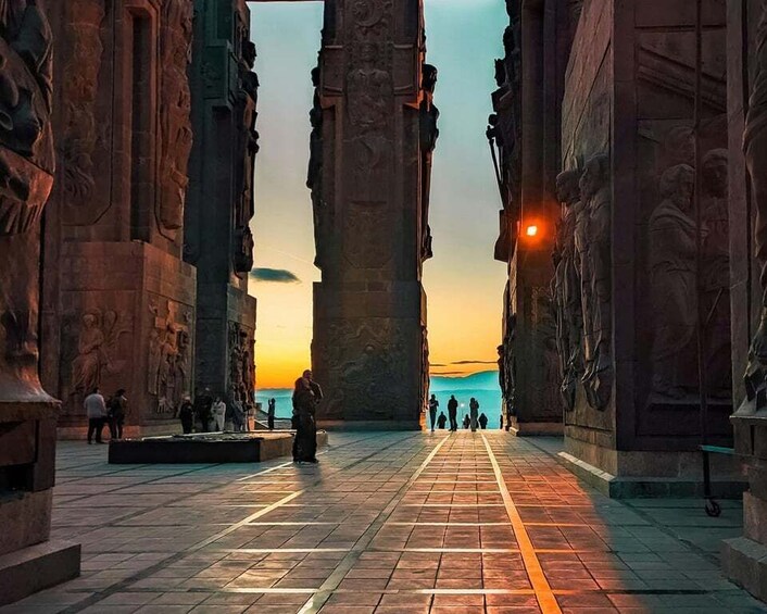 A historical site with ancient columns and a paved walkway leading to a distant view. 1