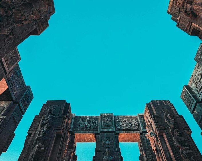 An ancient stone archway with intricate carvings against a clear blue sky. 2