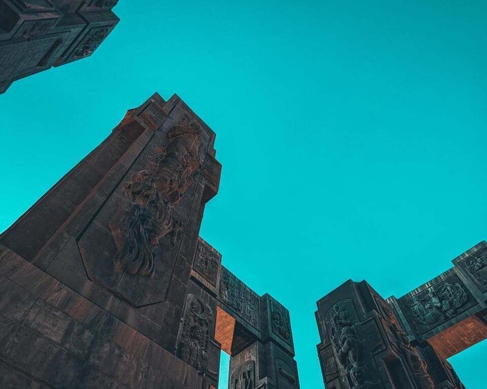 A tall, dark structure with intricate carvings against a clear blue sky. 4
