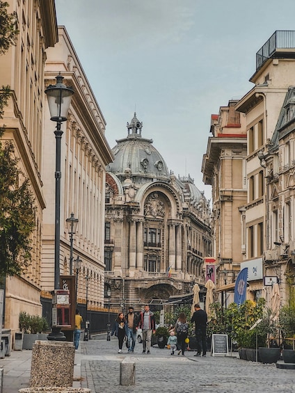 A historic building with ornate architecture and a dome, surrounded by cobblestone streets and pedestrians. 5