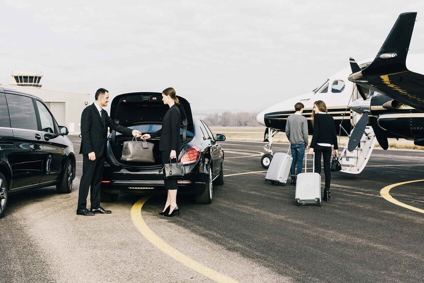 A private jet parked on a tarmac with people boarding and disembarking. 3