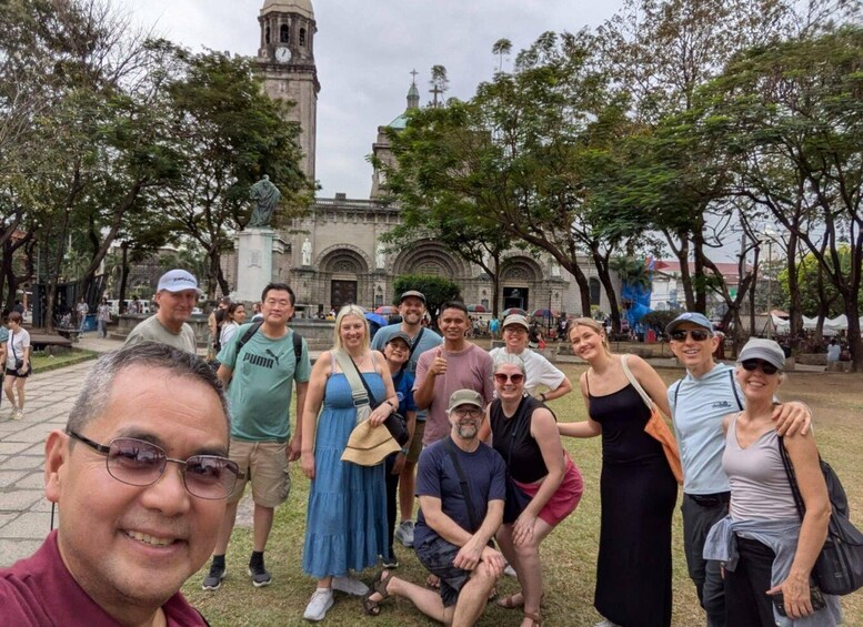 A group of people posing in a park with a historic building and a clock tower in the background. 2
