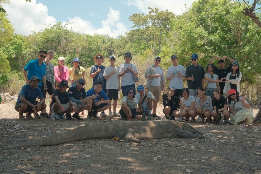 A group of people posing with a large snake in a natural setting. 5