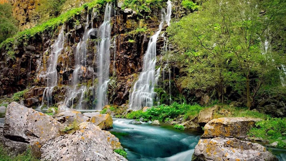 Una cascada en varios niveles que se precipita sobre rocas en un bosque verde y exuberante. 4