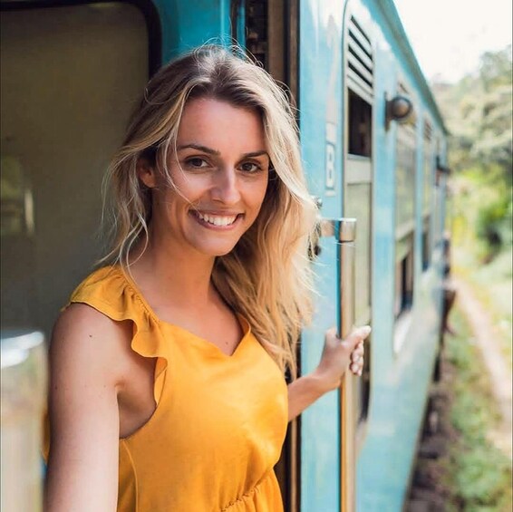 A person in a yellow dress standing next to a train. 2