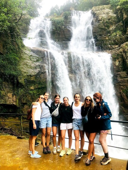 A group of people standing in front of a waterfall. 5