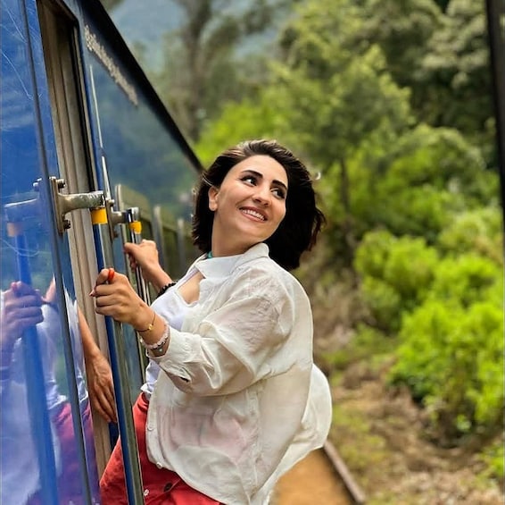 A person leaning out of a bus window, holding onto the window frame. 1