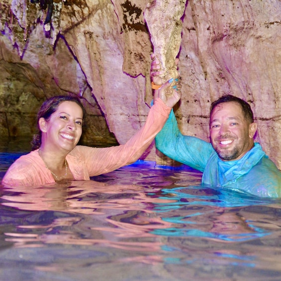 Two people in a pool with a cave-like background. 2