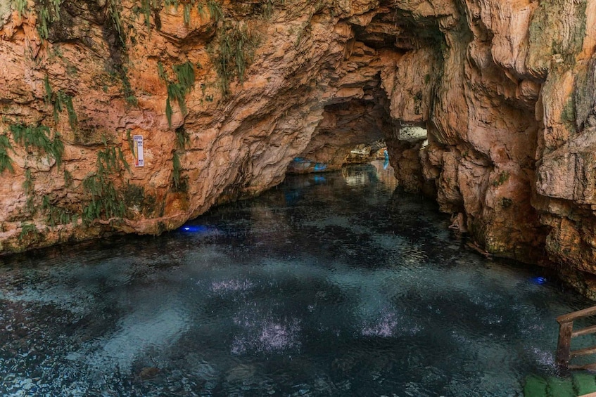 A cave with water reflecting light, rocky walls, and a wooden bridge. 3