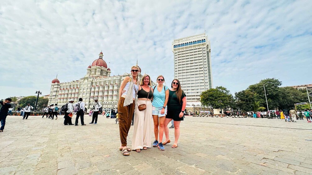 A group of people posing in front of a historic building with a large dome and a tall modern skyscraper in the background. 3