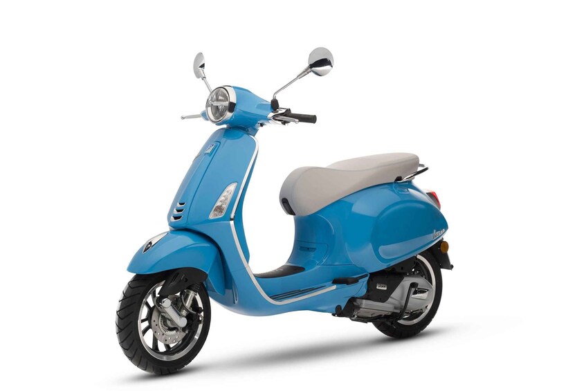 A blue scooter with a gray seat, chrome handlebars, and a rearview mirror. 1