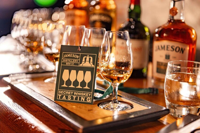 A whiskey tasting setup with glasses and a sign for Jameson Distillery. 5