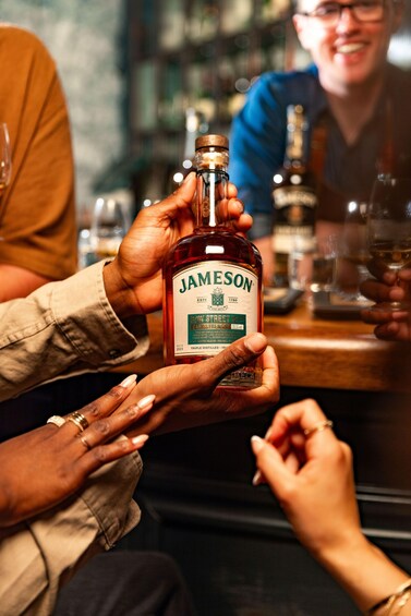 A person holding a bottle of Jameson whiskey. 2