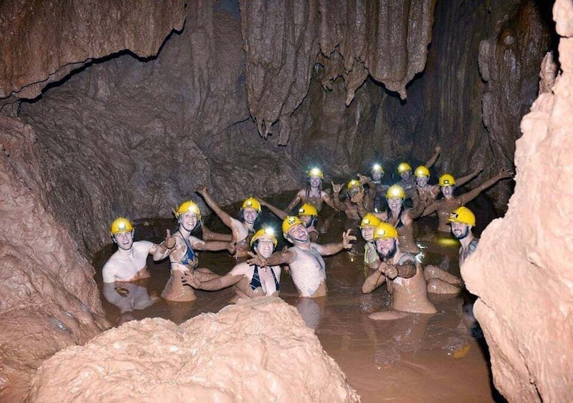 A group of people in a cave with muddy water and rocky walls. 1