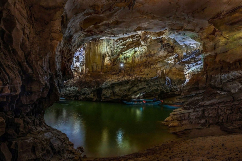 A cave with stalactites and a boat on a reflective water surface. 5