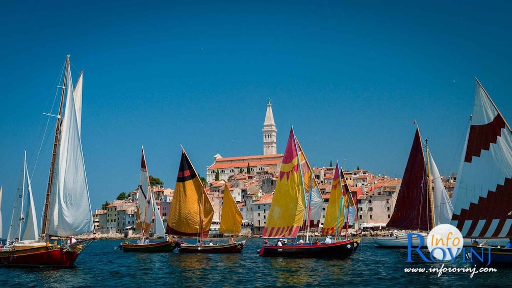 A harbor with colorful sailboats and a historic building with a tower in the background. 2