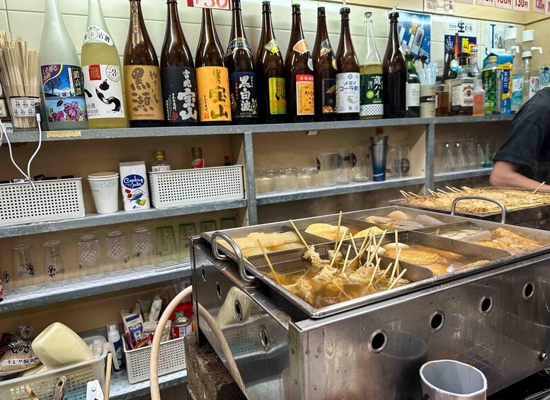 A variety of bottles on a shelf, a food fryer, and some cooking utensils. 4