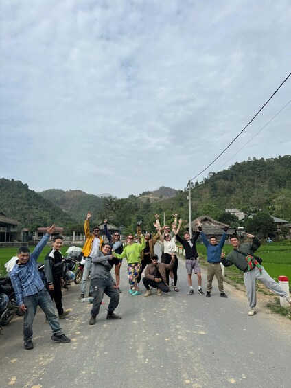 A group of people posing on a rural road with hills in the background. 5