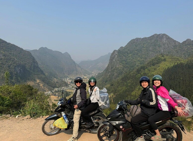 Four people on motorcycles with a mountainous landscape in the background. 1