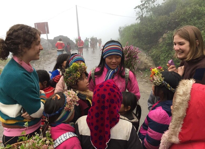 A group of people, some with flowers, gathered on a foggy road. 2