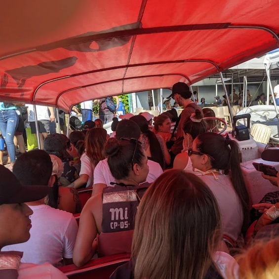 People seated under a red canopy, some wearing 'mi CP-05' vests. 3