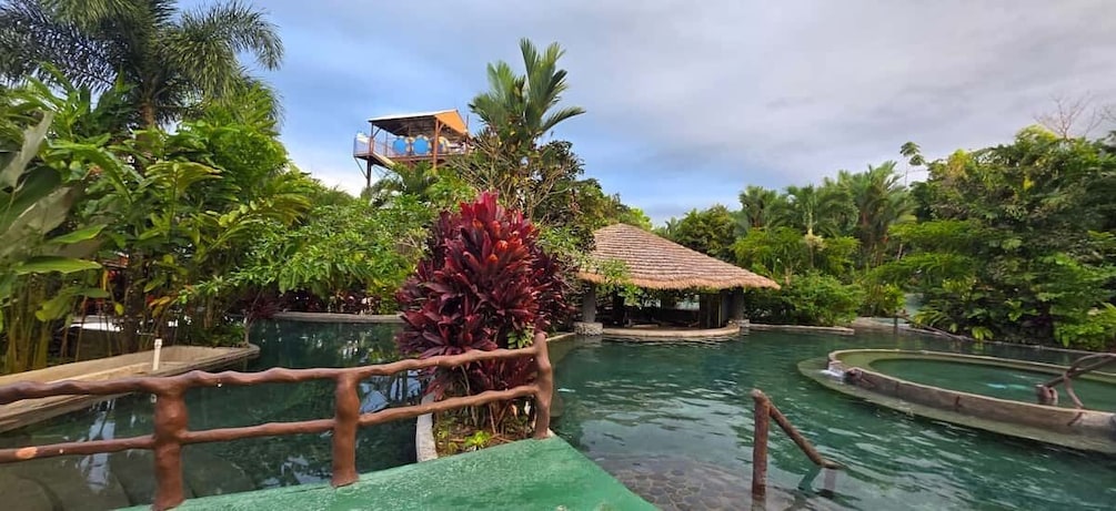 A tropical resort with a swimming pool, wooden boats, and lush greenery. 3